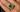 Close-up of a hand wearing a mid-century yellow gold ring with a Colombian emerald center and a ballerina-style halo of tapered baguette diamonds.