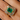 Close-up of a hand wearing a mid-century yellow gold ring with a Colombian emerald center and a ballerina-style halo of tapered baguette diamonds.